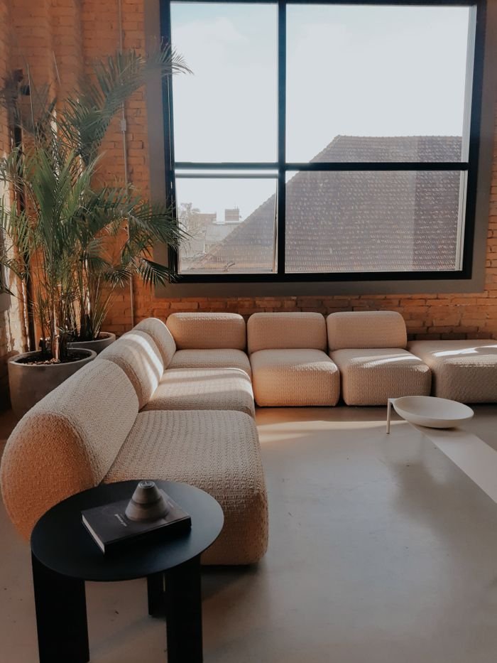 Cozy modern living room with beige sofas and large window, filled with natural light.